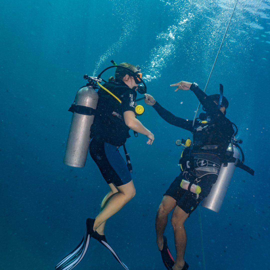 Phi Phi, Thailand - May 24 2019:  Learning to scuba dive involves mastering many underwater skills.  The scuba instructor on the right, is teaching the student the ‘controlled emergency swimming ascent’ drill.  A potentially life saving skill for underwater diving.